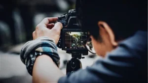 Videomaker che riprende con la fotocamera sul treppiede