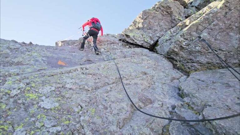 Escursionista che sale sulle rocce attrezzate con catene verso il Pizzo dei Tre Signori