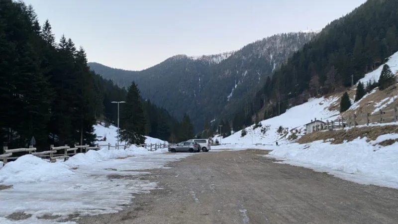 Parcheggio nella valle con le montagne e la neve a bordo strada