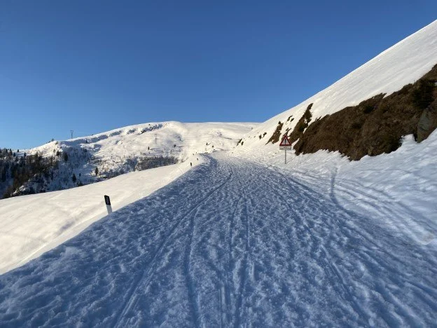 Strada innevata in salita con le cime sullo sfondo