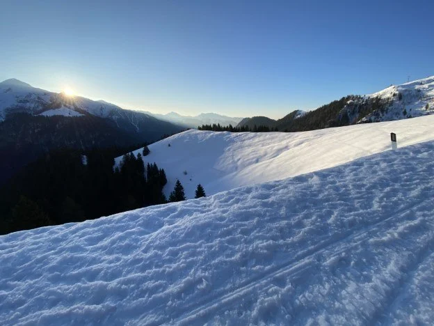 Sole all'orizzonte sopra il pendio innevato