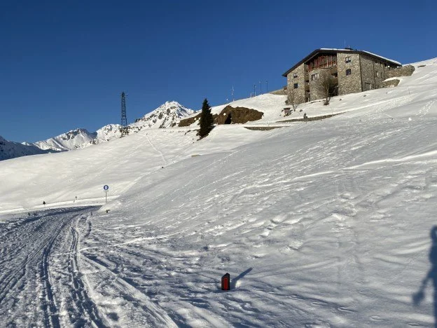 Rifugio in pietra sul pendio innevato con un impianto di risalita