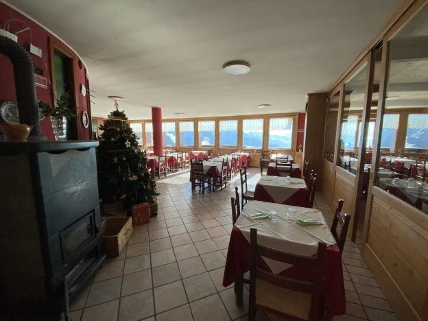 Sala da pranzo del rifugio con tavoli apparecchiati e l'albero di Natale