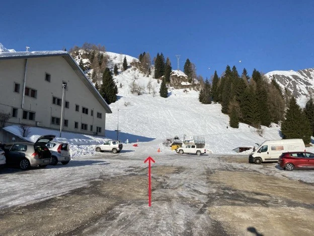 Parcheggio innevato con freccia rossa che indica la direzione