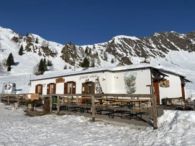 Baita del Camoscio sulla neve con le montagne alle spalle